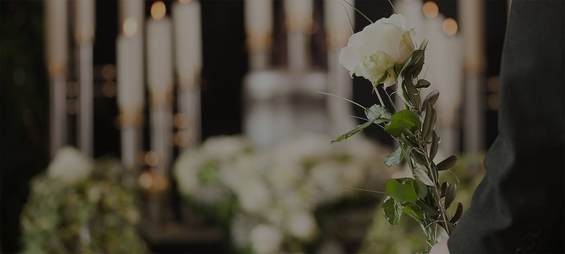 Person hält weiße Blume während Beerdigung